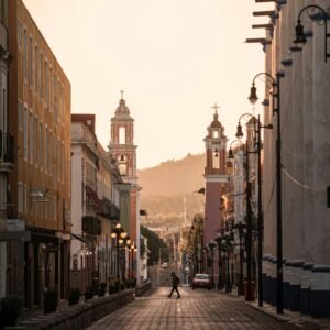 Scenic view of a historic street with iconic towers in Puebla, Mexico at sunset.